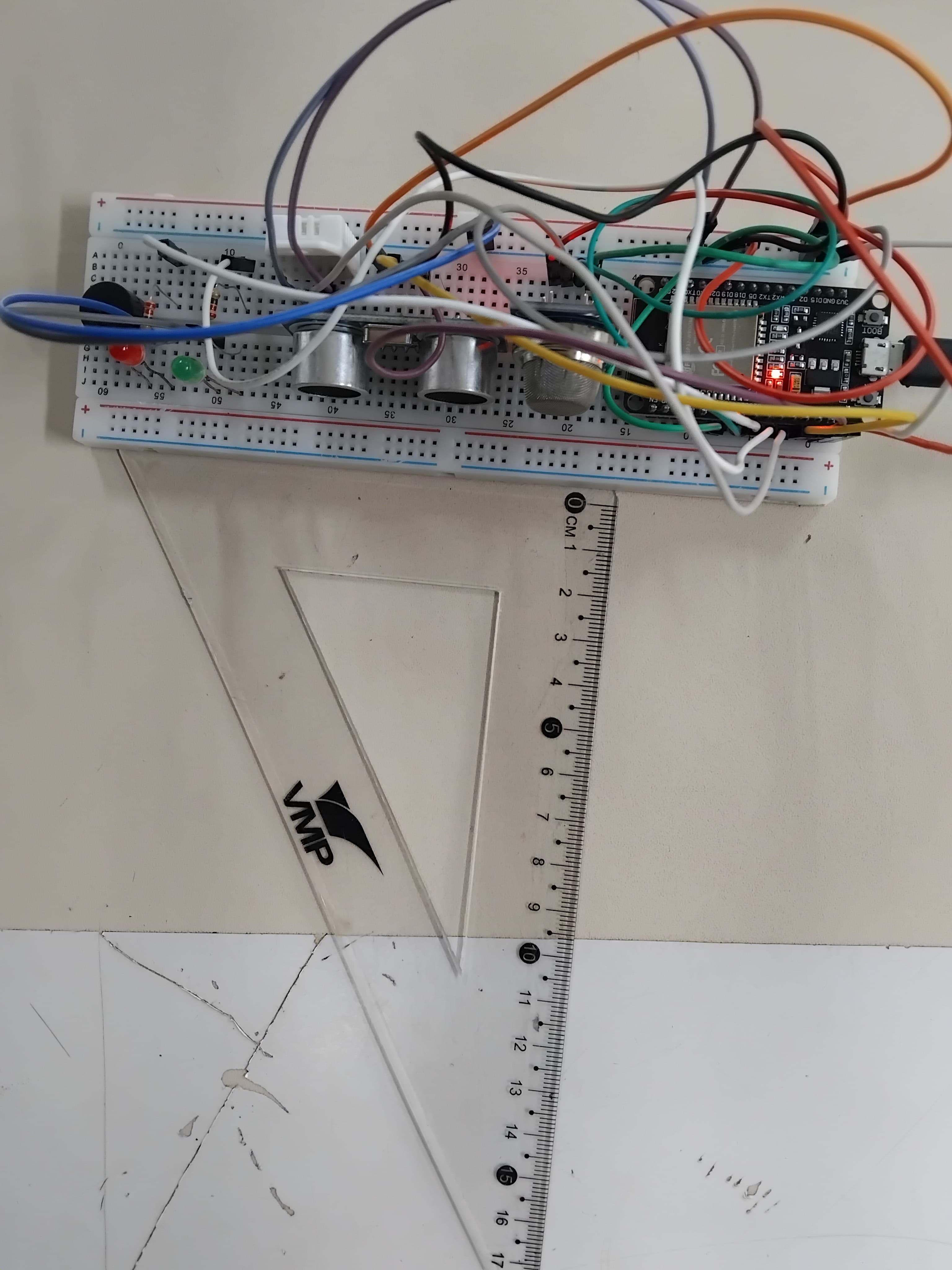 Protótipo em protoboard com microcontrolador ESP32, dois sensores ultrassônicos HC-SR04 e LEDs, ao lado de régua e esquadro